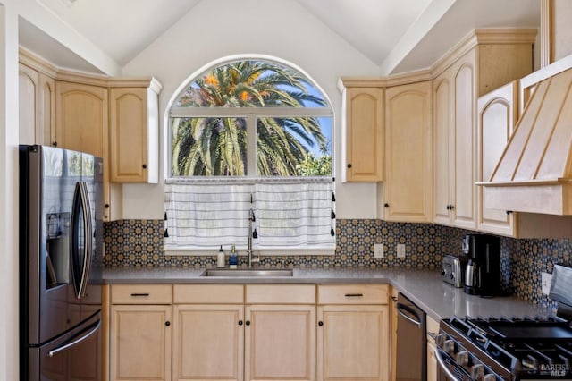 kitchen featuring light brown cabinetry, stainless steel appliances, a sink, and lofted ceiling