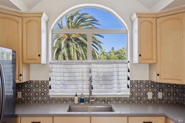 kitchen featuring light brown cabinetry, fridge, plenty of natural light, tasteful backsplash, and a sink