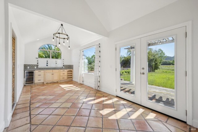 entryway with french doors, baseboards, lofted ceiling, wine cooler, and light tile patterned flooring