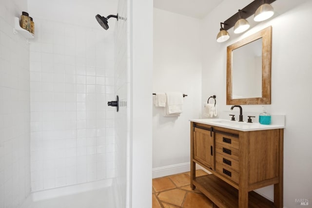 full bath with baseboards, tiled shower, and vanity