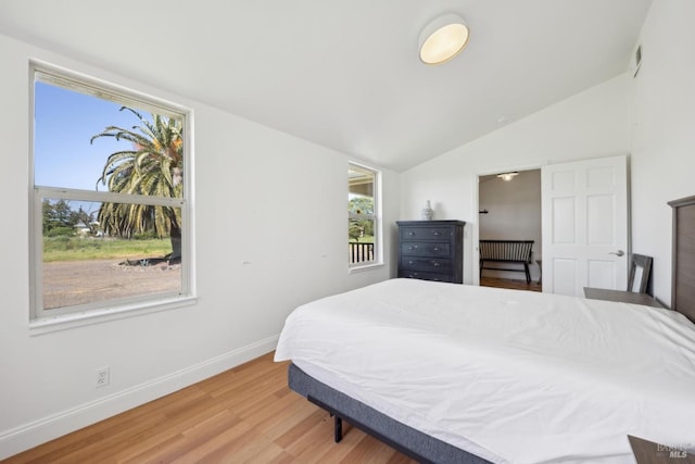 bedroom featuring baseboards, light wood finished floors, lofted ceiling, and visible vents