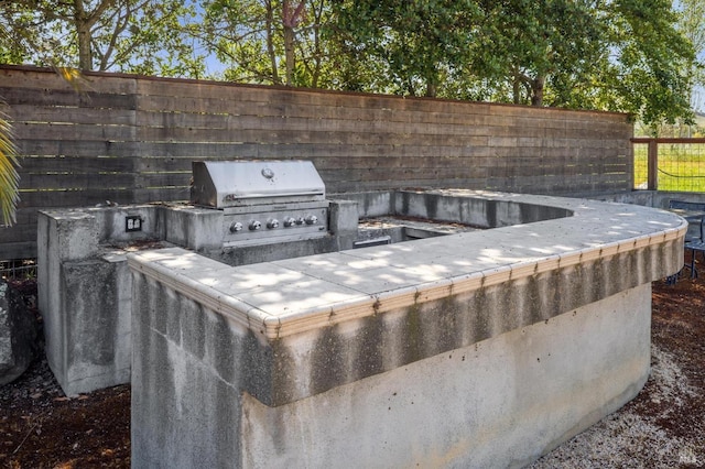 view of patio with exterior kitchen, grilling area, and fence