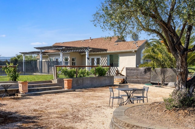 rear view of house with a pergola, fence, roof with shingles, and stucco siding