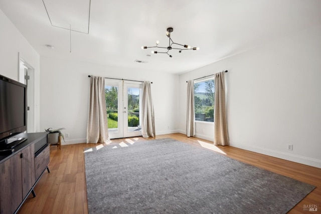 unfurnished living room featuring baseboards, visible vents, attic access, and light wood-style floors