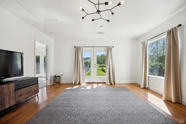 unfurnished living room featuring french doors, attic access, plenty of natural light, and wood finished floors