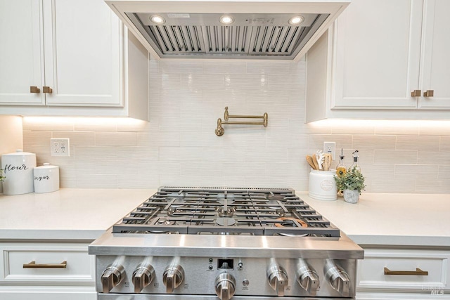 kitchen featuring light countertops, backsplash, white cabinets, and custom range hood