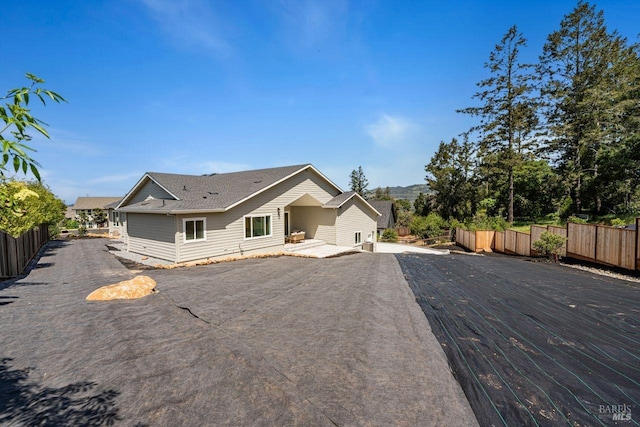 back of house featuring a shingled roof and fence