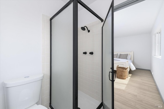 ensuite bathroom with ensuite bath, toilet, baseboards, a shower stall, and wood finished floors