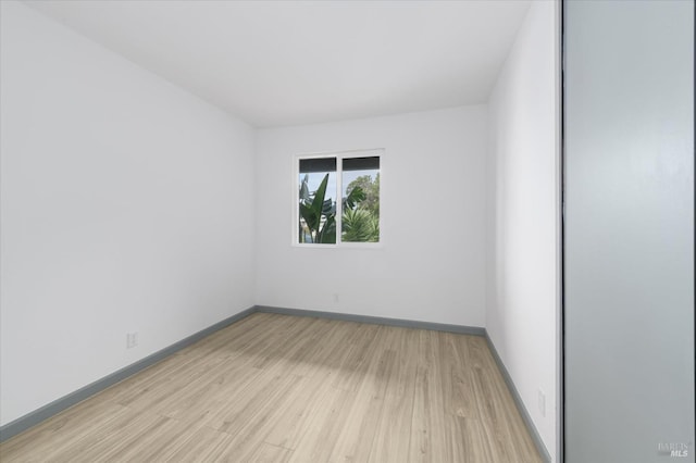empty room featuring baseboards and light wood finished floors