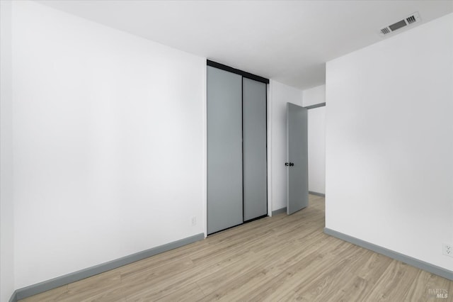 empty room with baseboards, visible vents, and light wood-style floors