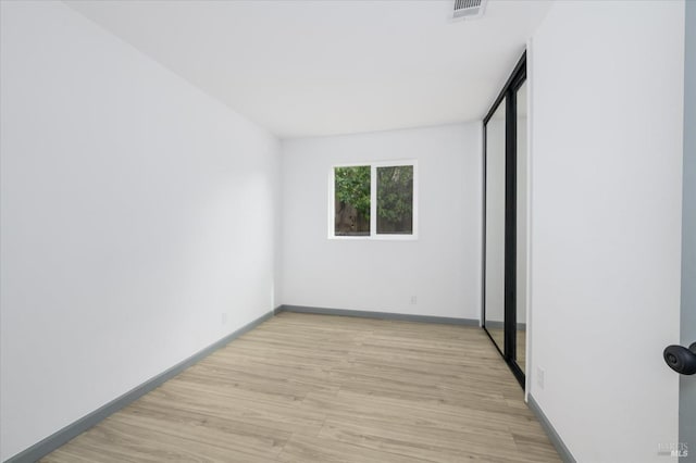 unfurnished room with baseboards, visible vents, and light wood finished floors