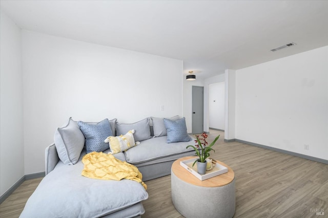 living room with visible vents, baseboards, and wood finished floors