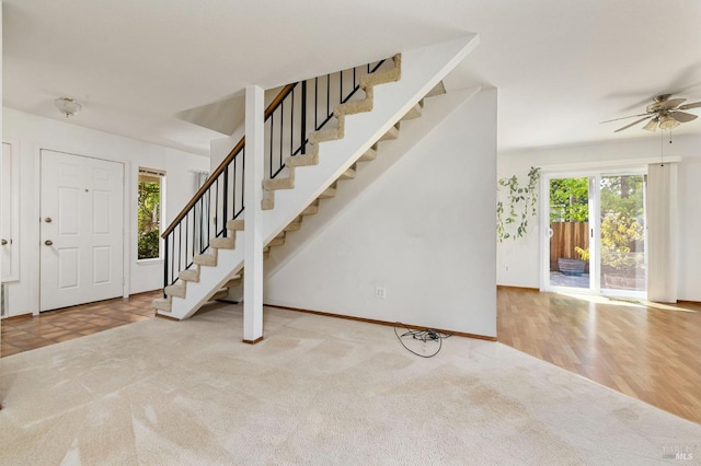 entrance foyer featuring baseboards, carpet flooring, stairs, and ceiling fan