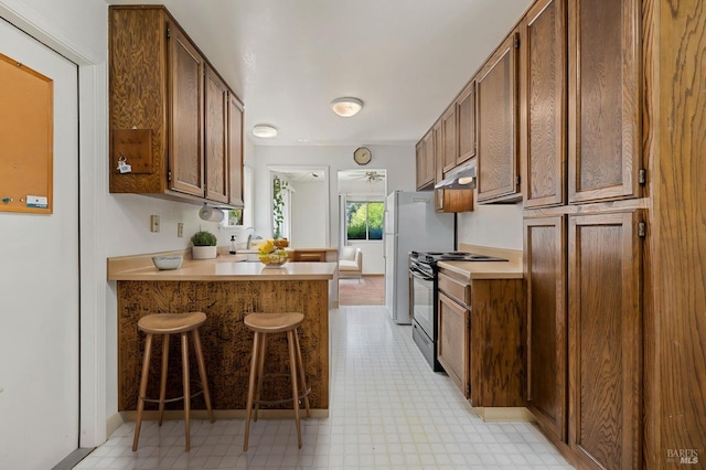 kitchen featuring a sink, a breakfast bar area, light countertops, a peninsula, and black range with electric cooktop