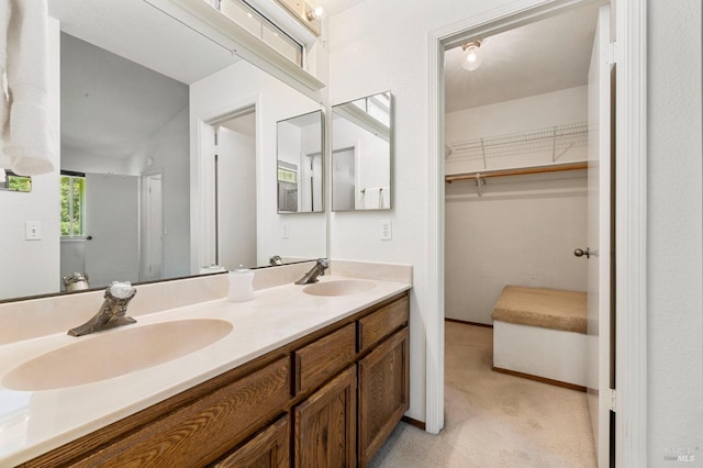 full bath with double vanity, a walk in closet, and a sink