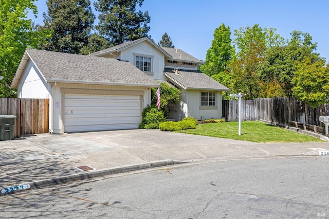 traditional home featuring an attached garage, a front lawn, fence, and concrete driveway