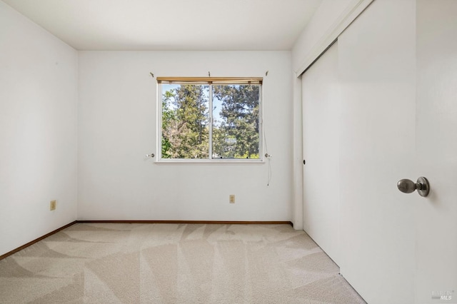 spare room featuring baseboards and light carpet