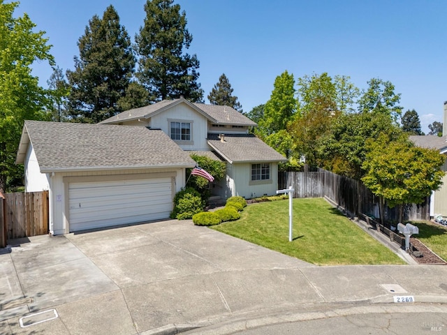 traditional-style house featuring fence, a front yard, roof with shingles, an attached garage, and driveway
