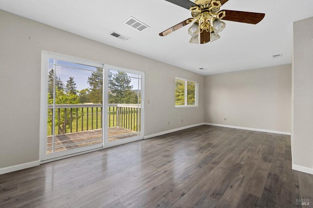 unfurnished room with a ceiling fan, wood finished floors, and visible vents