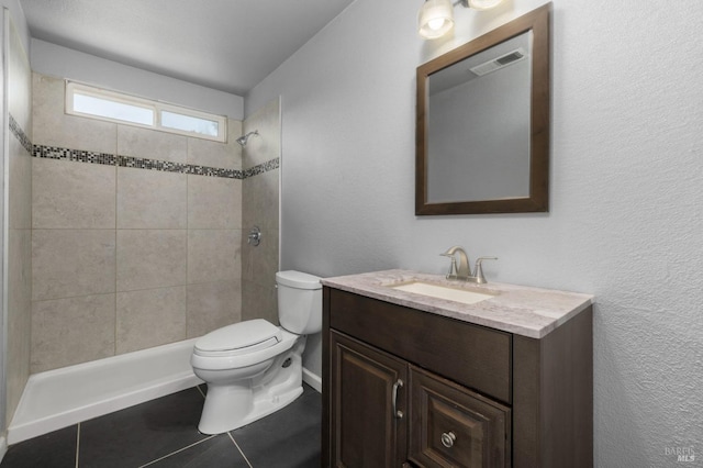 bathroom with a tile shower, tile patterned flooring, vanity, toilet, and visible vents