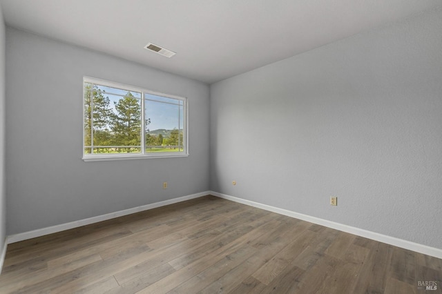 spare room with baseboards, wood finished floors, and visible vents