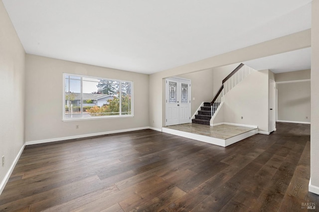 unfurnished living room with baseboards, stairs, and dark wood finished floors