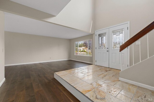 foyer entrance featuring stairs, baseboards, a high ceiling, and wood finished floors