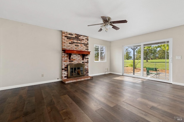 unfurnished living room with baseboards, a ceiling fan, wood finished floors, and a brick fireplace