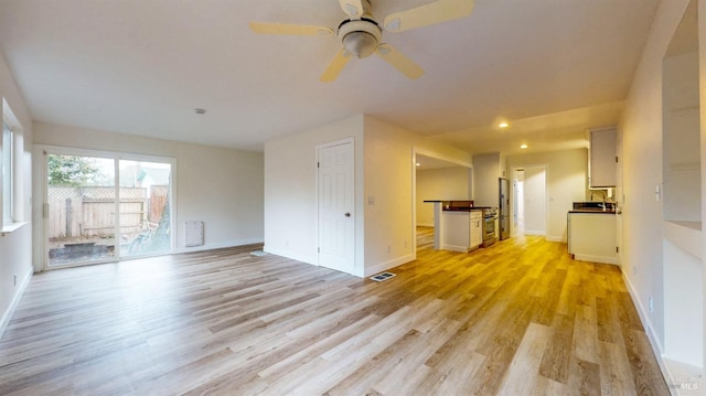 unfurnished living room with baseboards, visible vents, ceiling fan, and light wood-type flooring