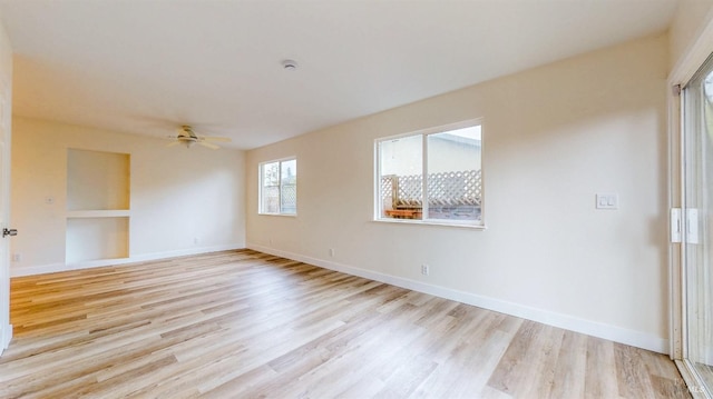 spare room with a ceiling fan, baseboards, and light wood finished floors