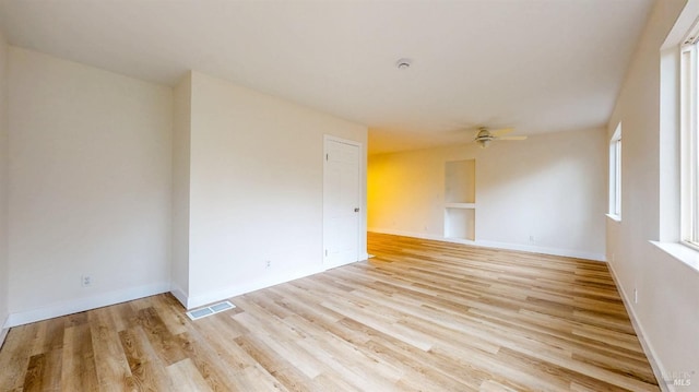 empty room featuring a ceiling fan, baseboards, visible vents, and light wood-style flooring