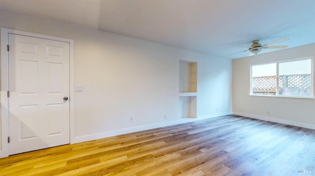 unfurnished room featuring baseboards, light wood-style flooring, and ceiling fan