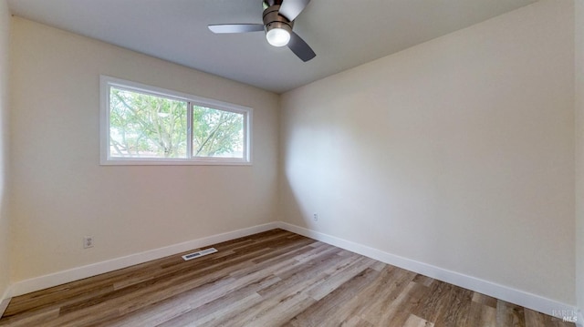spare room with baseboards, a ceiling fan, light wood-type flooring, and visible vents