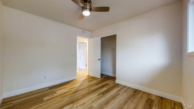 empty room with baseboards, a ceiling fan, and light wood-type flooring