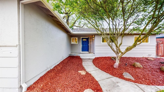 property entrance with stucco siding and fence