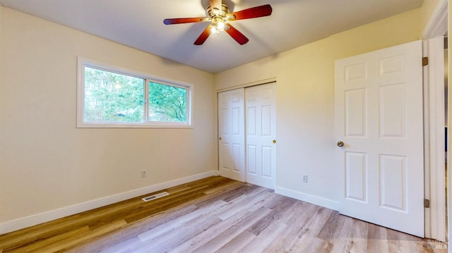 unfurnished bedroom with ceiling fan, light wood finished floors, baseboards, visible vents, and a closet