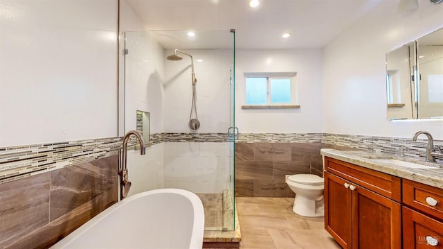 full bath featuring vanity, recessed lighting, a freestanding tub, tile walls, and a shower stall