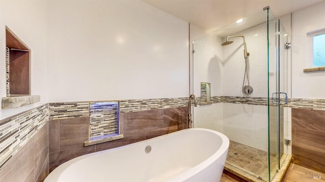 full bathroom with a stall shower, wainscoting, a soaking tub, and tile walls