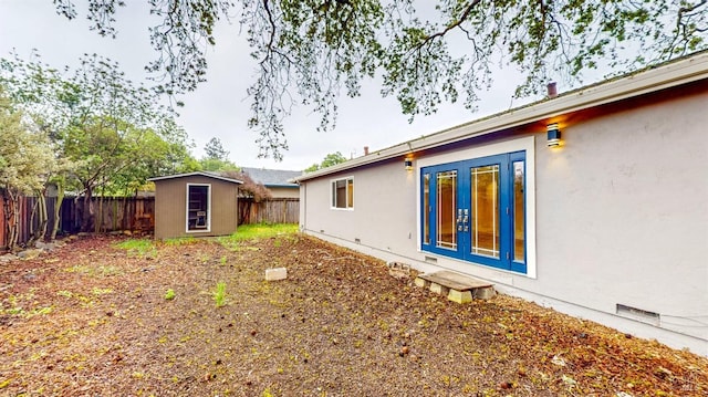 view of yard featuring french doors, a storage unit, an outdoor structure, and a fenced backyard
