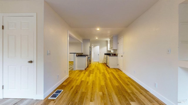 hall with baseboards, light wood-type flooring, recessed lighting, and visible vents