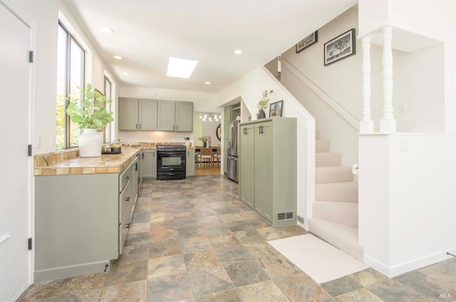 45 Laurel Grove Ave, Kentfield, CA 94904 - kitchen with freestanding refrigerator, stone finish floor, tile countertops, black range with electric stovetop, and gray cabinetry