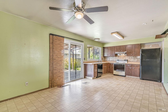 kitchen with light countertops, baseboards, tasteful backsplash, under cabinet range hood, and black appliances