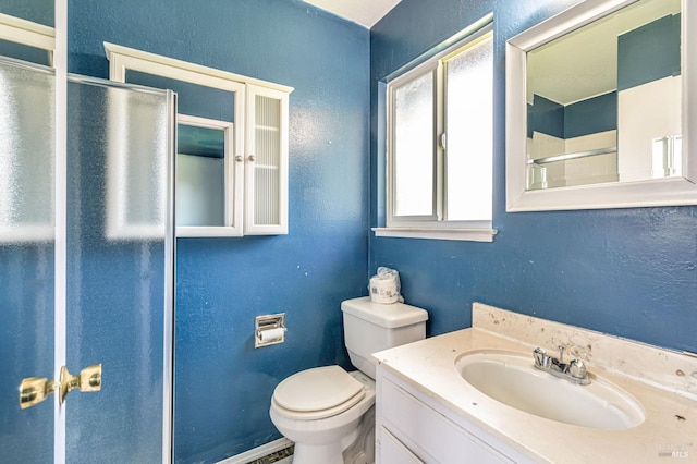 full bathroom with an enclosed shower, toilet, a textured wall, and vanity