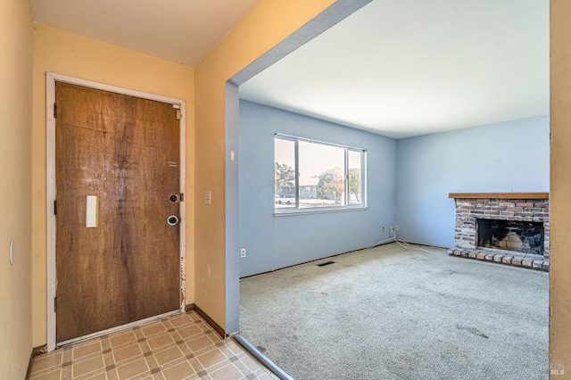 carpeted foyer featuring visible vents and a fireplace