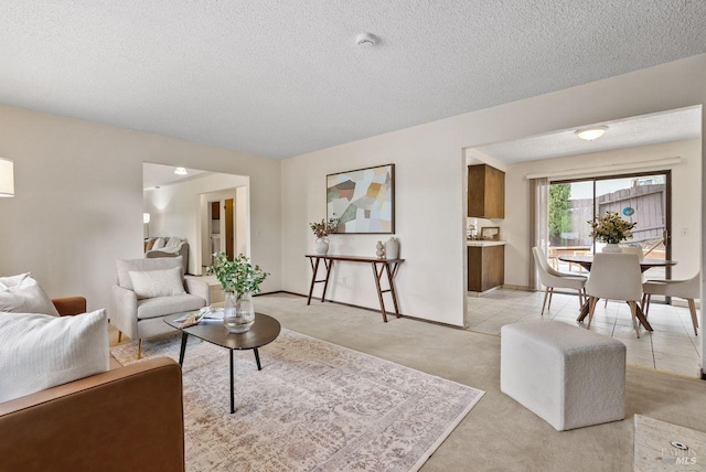 living room with a textured ceiling, light colored carpet, and baseboards