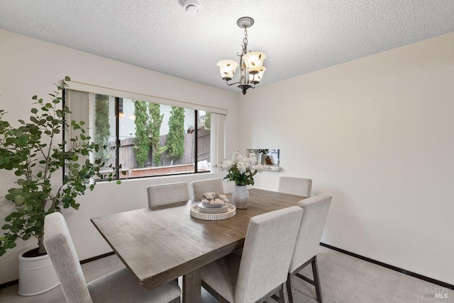 dining area with a textured ceiling, a notable chandelier, light carpet, and baseboards
