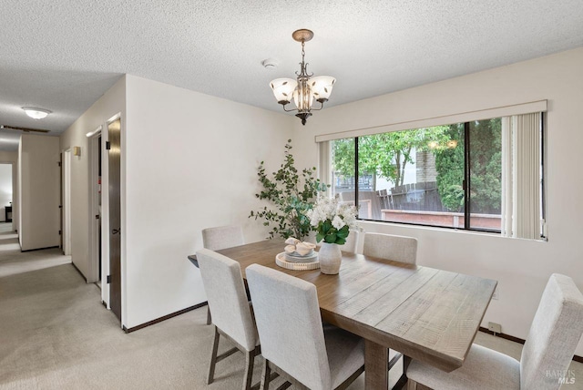 dining space with a chandelier, a textured ceiling, light colored carpet, and baseboards