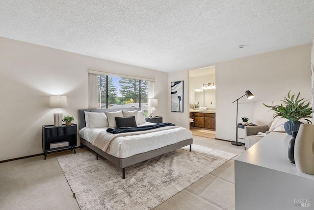 bedroom with a textured ceiling, light colored carpet, and ensuite bathroom