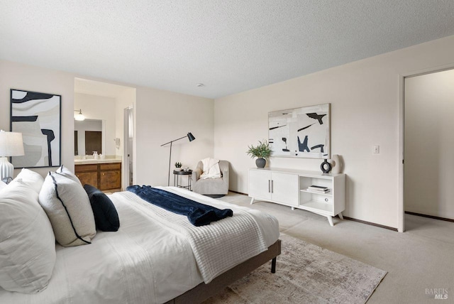 bedroom with light colored carpet, connected bathroom, a textured ceiling, and baseboards