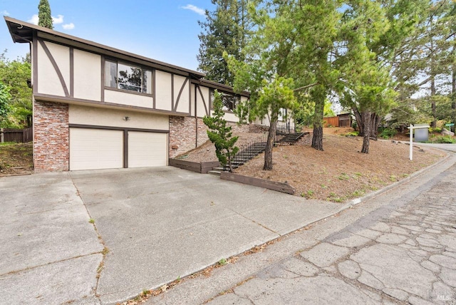 tudor home featuring a garage, stucco siding, concrete driveway, and brick siding